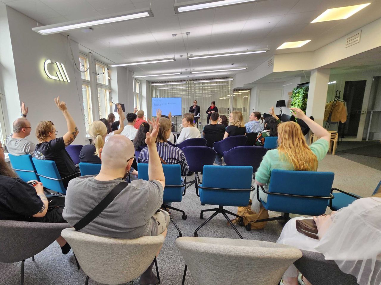 A full room with many hands raised during the talk