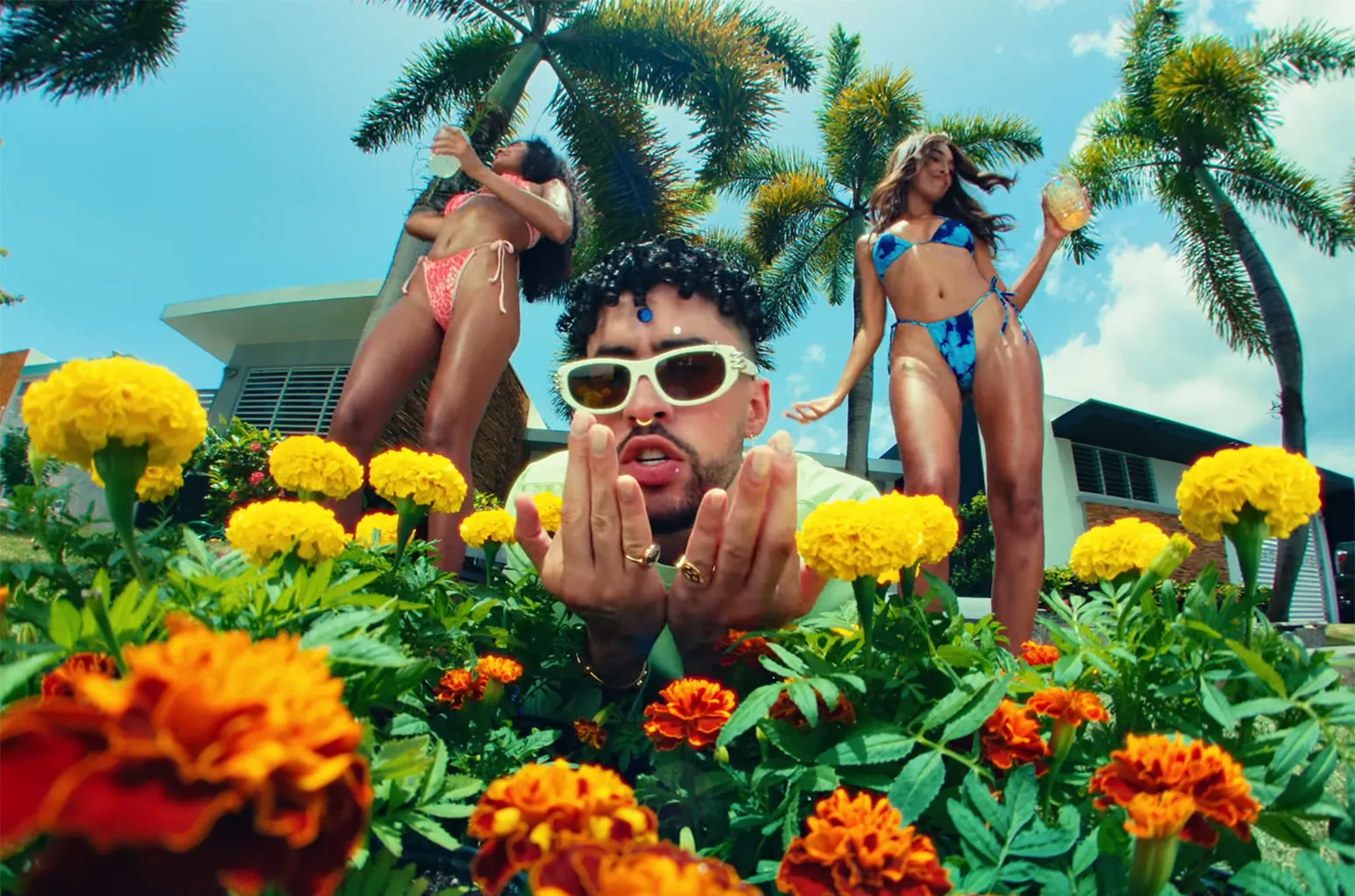 Bad Bunny music video still with bright flowers and palm trees